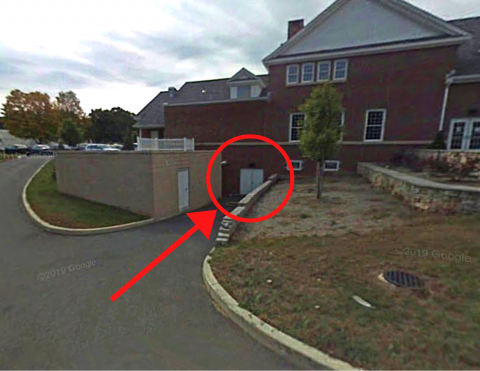 A photograph of the rear basement entrance of the library circled in red. The entrance is to the left of the patio area.