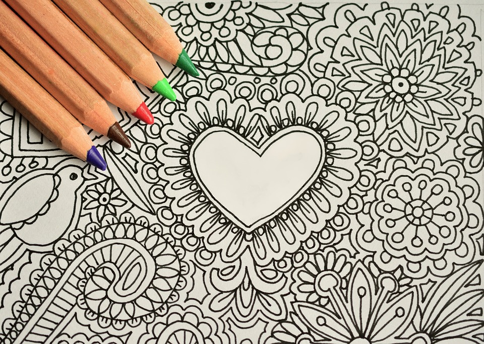 Blank coloring page with various designs and heart in the center with 5 colored pencils
