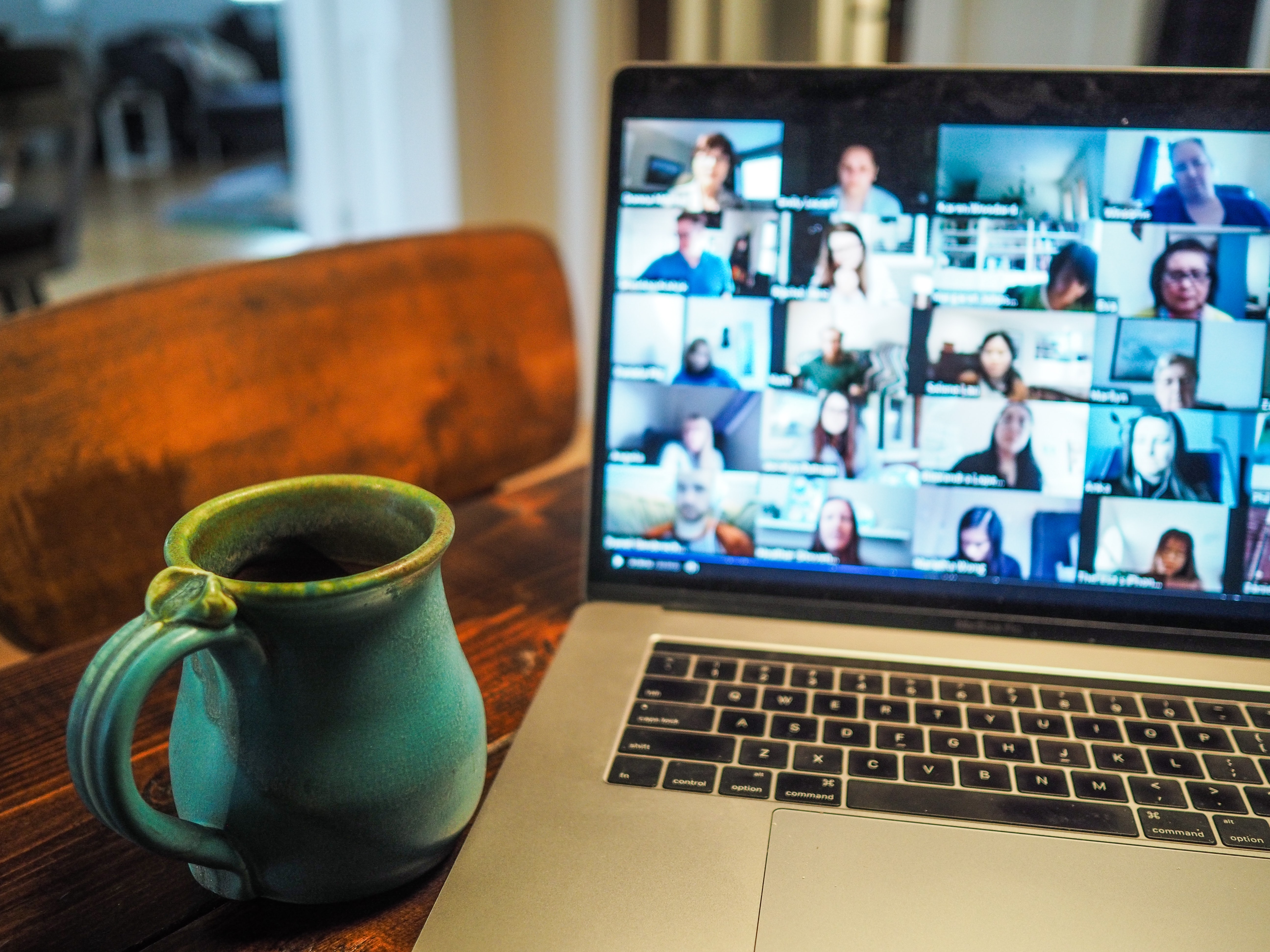 A mug next to a laptop with a screen showing a video conference