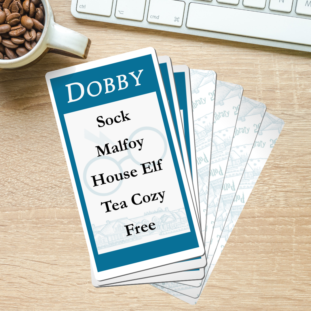 Picture of a stack of cards for the card game Taboo. The top card is overturned and the words are visible. "Dobby" is the word to be guessed and "Sock, Malfoy, House Elf, Tea Cozy, and Free" are the taboo words.