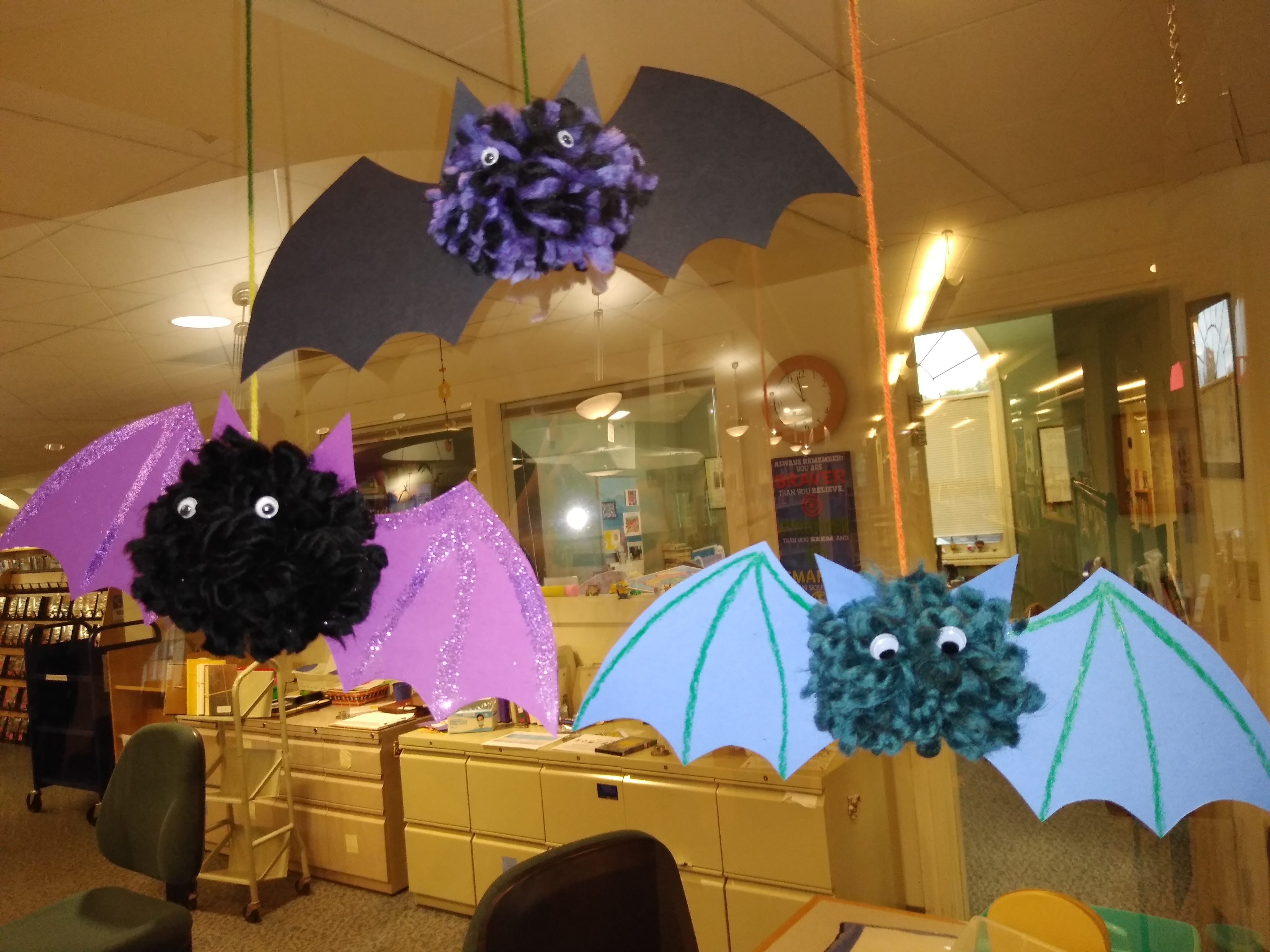 Image of three bat made from yarn and paperhanging in the library.