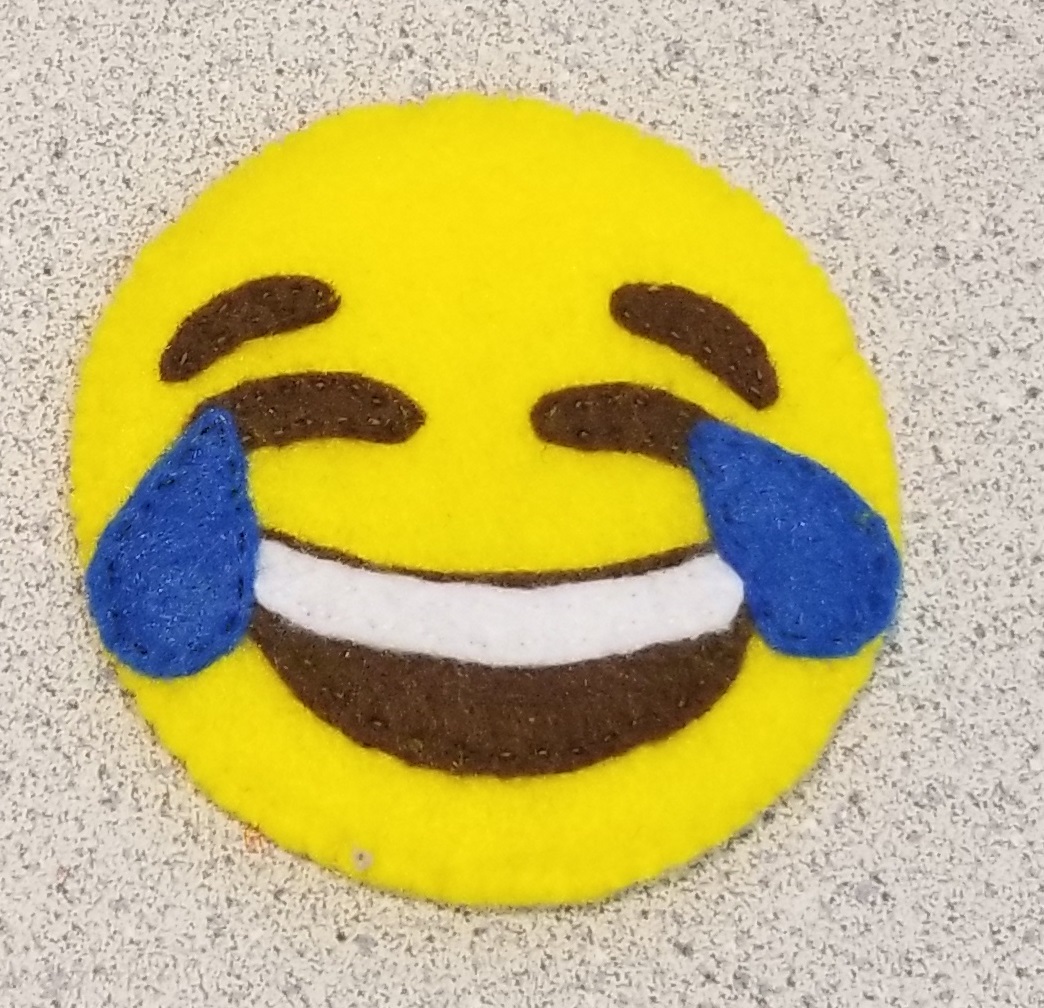 A yellow felt Crying Laughing Emoji 