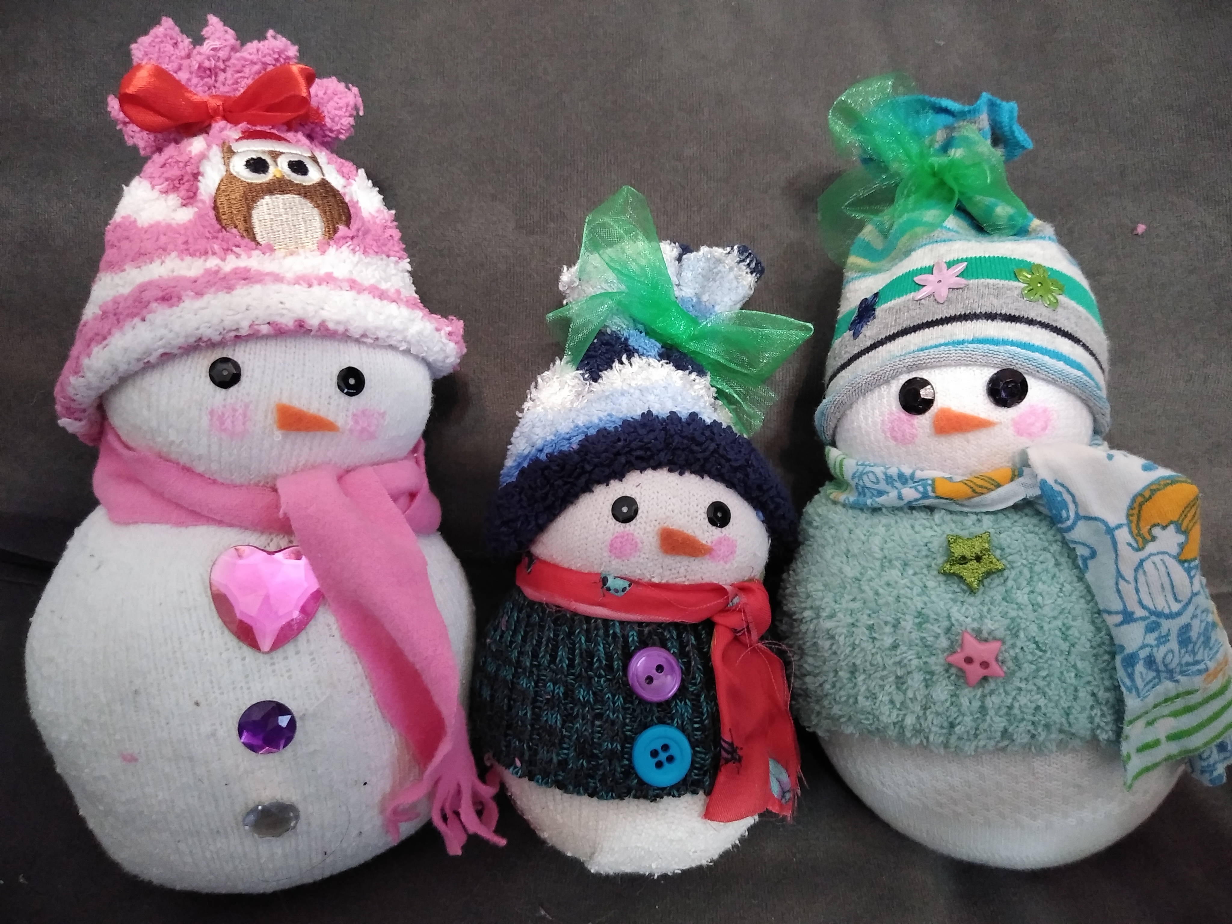 Three snowmen made out of white socks and craft materials.