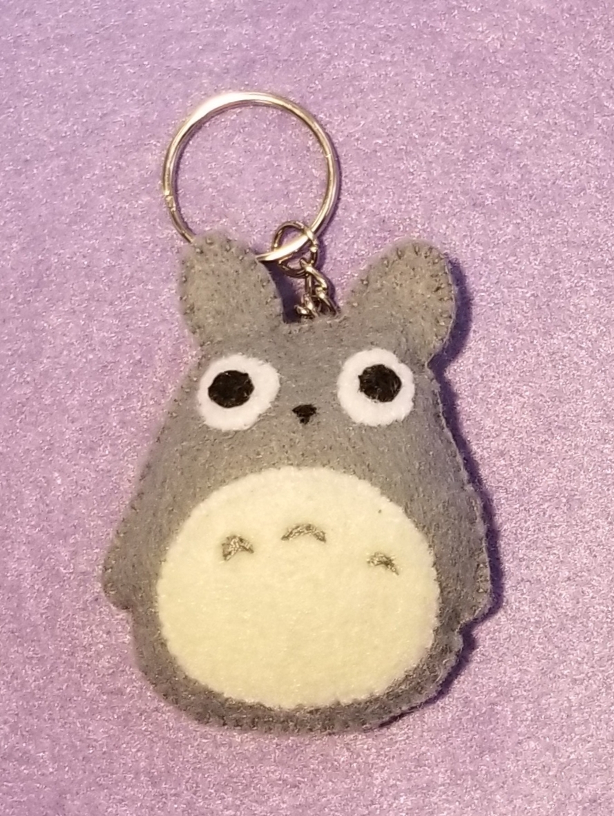 A gray felt plush keychain that looks like the Miyazaki character Totoro