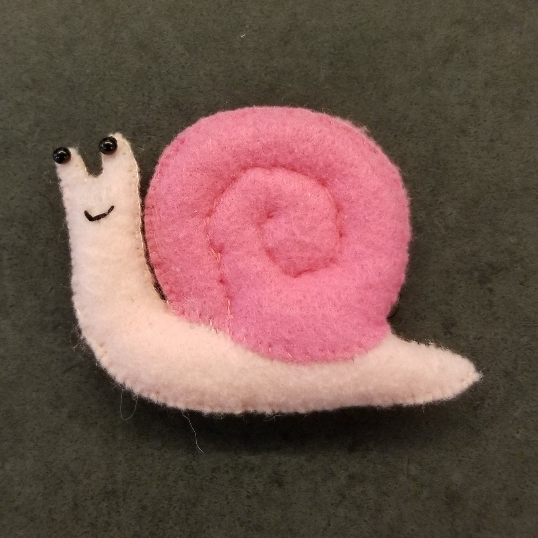 A smiling snail plush with a light pink body and medium pink shell.