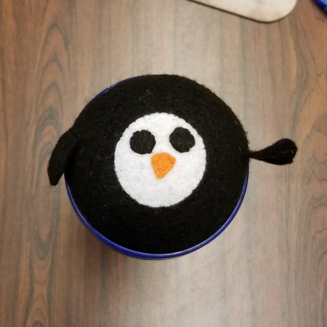 A spherical penguin plush with a circular face and a waving arm/wing
