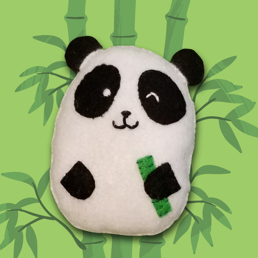 An oval shaped panda plush holding a piece of bamboo and smiling