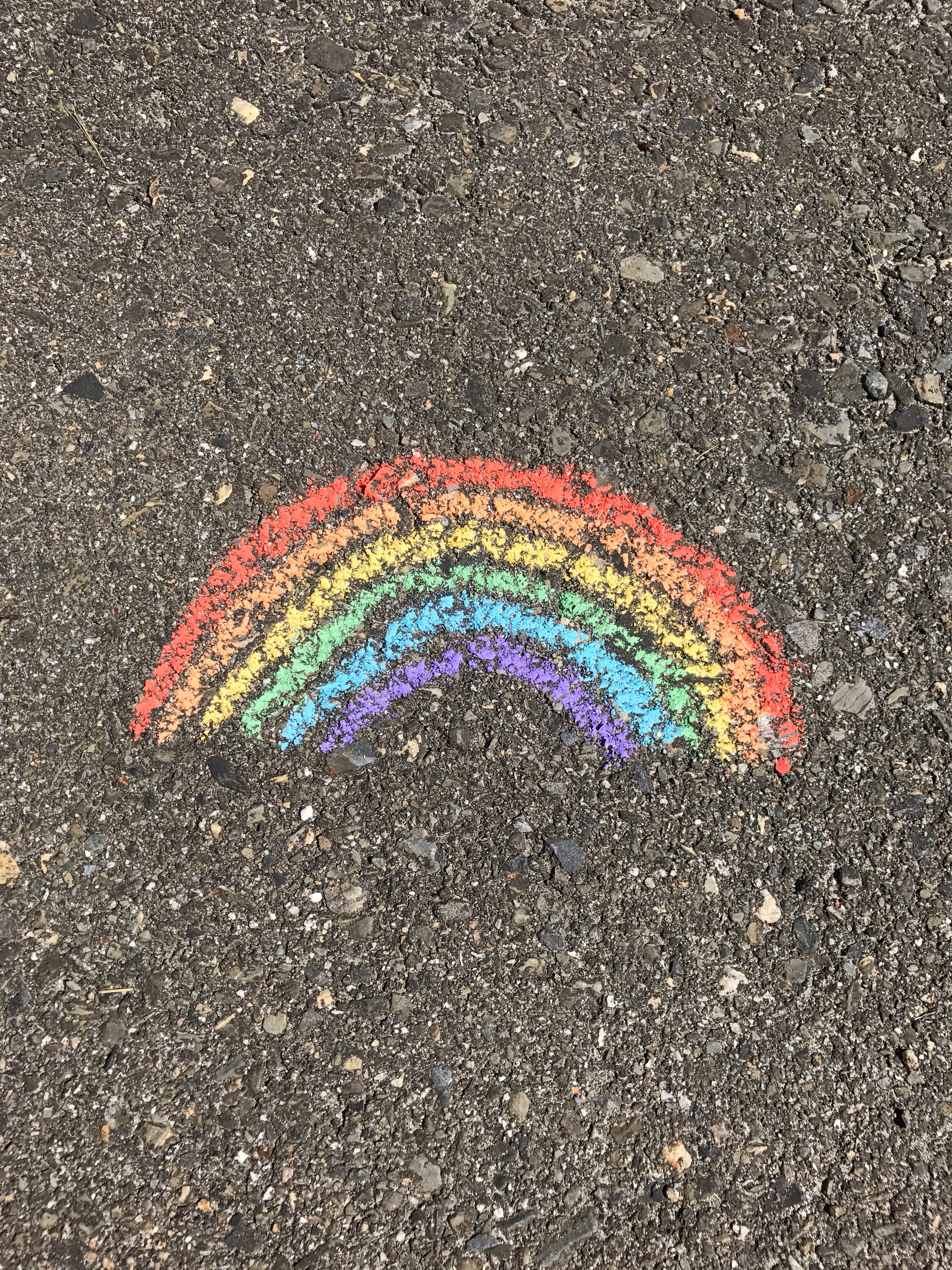A simple chalk drawing of a rainbow on pavement