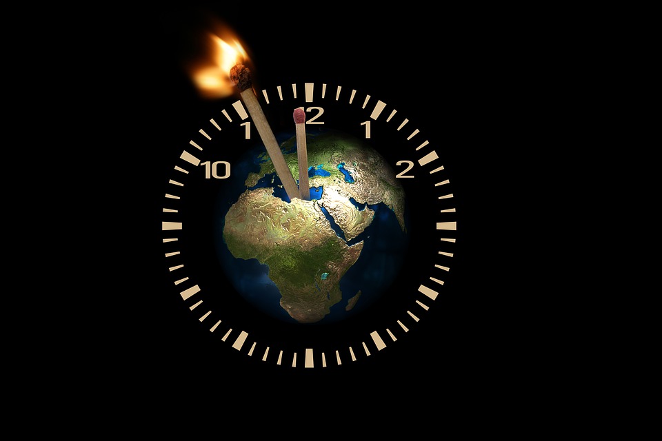 The earth surrounded by a time clock. Time is almost out, as shown with burning match sticks.