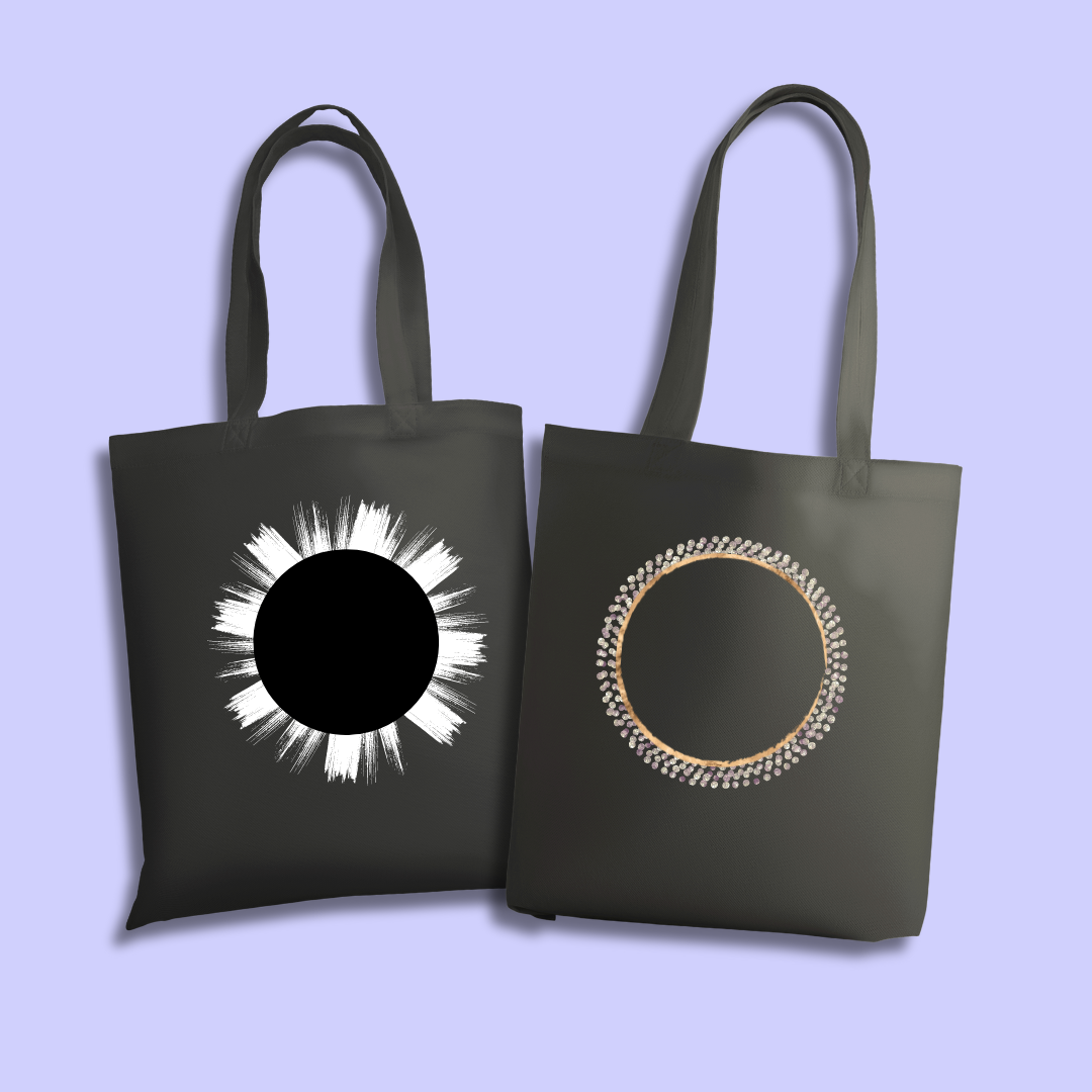 Two black tote bags with different painted eclipse shapes on them