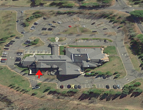 A top down satellite view of the library with the front entrance indicated by text a red arrow pointing to where the basement rear entrance is located.