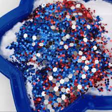Baking soda and vinegar mixture in a blue star shaped dish with red, white and blue glitter on top.