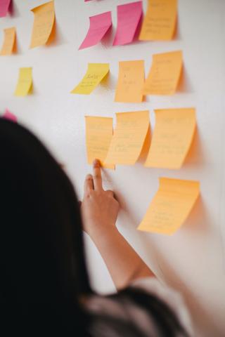 A person with long hair in front of a wall of post it notes