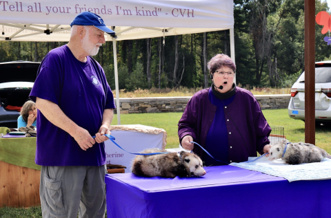 A picture of Pam and Jim Lefferts with two opossums doing a presentation