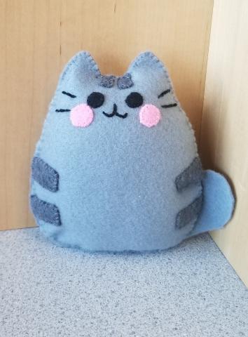 An example of the craft - a smiling gray mini plush that looks like the cat Pusheen.