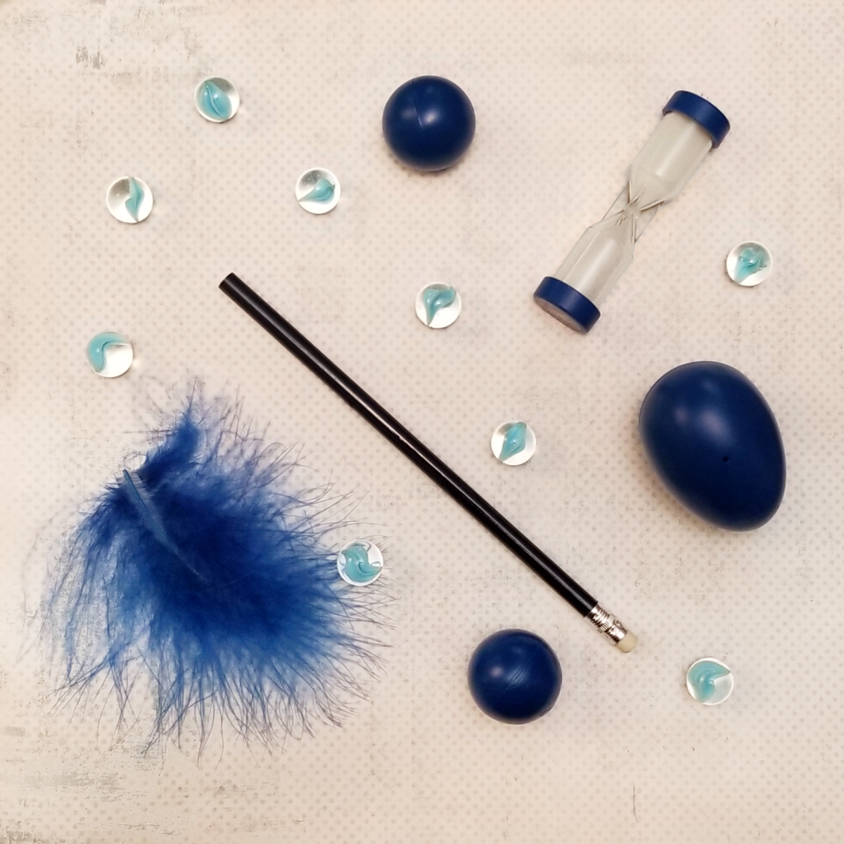A feather, marbles, pencil, ping pong balls, plastic egg, and minute timer