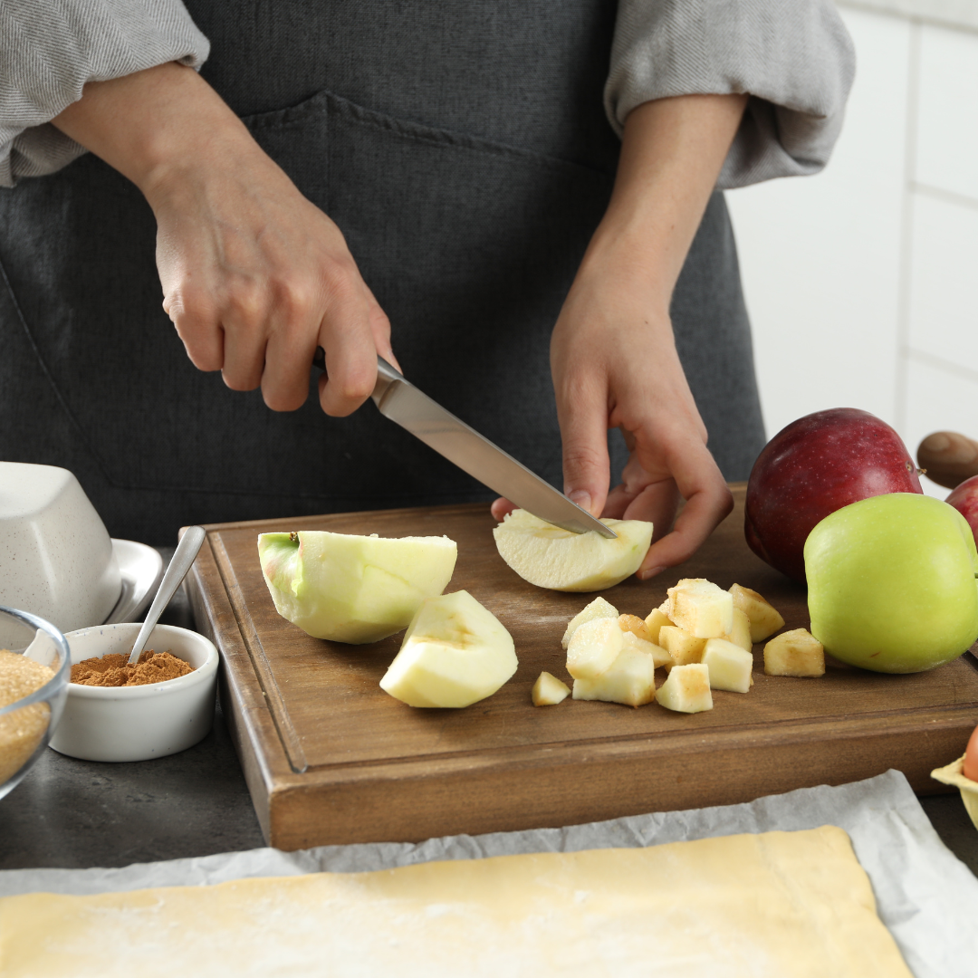 hands slicing apples on a cutting board