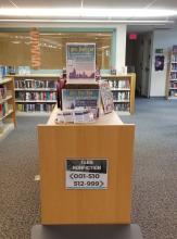 A picture of card packs and signage on top of the Teen Nonfiction shelf at the Southbury Public Library